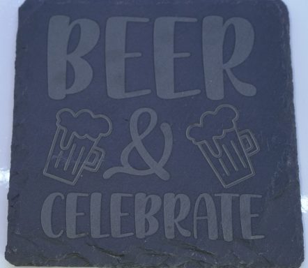Schieferplatte mit der Aufschrift "BEER & CELEBRATE" und zwei Bierkrügen.